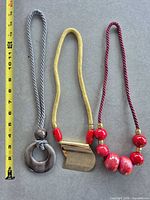 All three necklaces laid out beside tape measure showing length reference
