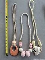 All three cord necklaces showing pendants and beads beside ruler for scale