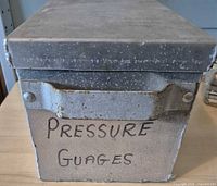Front view showing box, lid in place, pressure gauges label