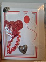 Front view of sealed greeting card kit showing red balloons, curling ribbon and pewter heart base