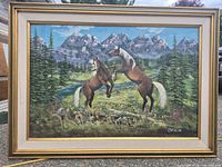 Front view of framed painting depicting two horses in mountain landscape