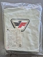 Front view of packaged Faulkner white tire cover showing logo and included size chart