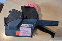 Full view of Avery Dennison 216 pricing gun with roll of orange labels installed