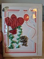 Front of one sealed greeting card showing pewter rose holder and balloon design
