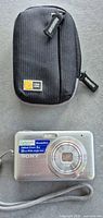 Front view of Sony DSC-W310 camera beside Case Logic pouch