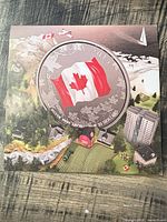 Front of presentation folder showing enlarged coin image and Canadian landscape art