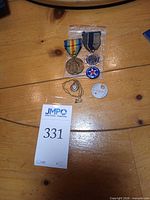 Front view of all five items laid out: WWI Victory Medal, American Legion medal, Aeronautical Lodge pin, locket necklace, metal ID tag