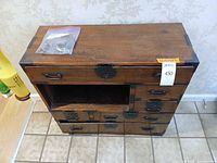 Front view of chest showing drawers, metal hardware, spare hardware bag on top
