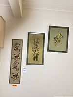 All three framed needlepoint bird artworks displayed on wall