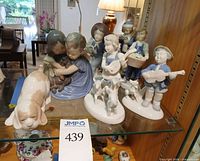 Group shot of all seven porcelain figurines in cabinet