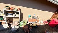 Wide view of shelving and ground showing mixed pots, planter box, hanging basket frames