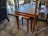 Three teak veneer nesting tables stacked