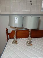Pair of crystal lucite lamps with gray drum shades on bed