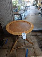 front view of round rattan bamboo side table on tripod legs