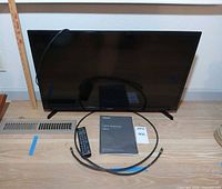 Front view of Samsung 32" TV with remote, manual, coax cable visible