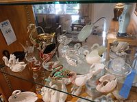 Overview of mixed swan and duck figurines on glass shelf