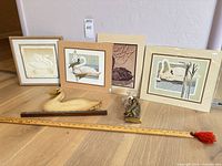Group shot of all prints, carved wood swan, brass knocker and ruler for scale