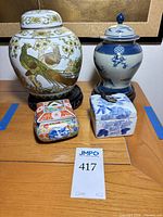 Full lot showing two lidded jars on stands and two trinket boxes