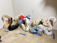 Group view of all six swan pieces with flowers and ruler for scale