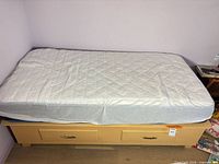 Twin mattress on light wood platform bed frame
