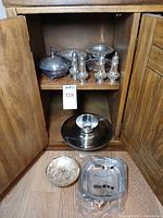 Cabinet shelf showing covered dish, four shakers, pedestal compote, pink-tinted handled dish and other items