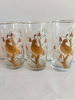 Front view of three tumblers showing gold bird and pear motif