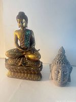 Seated gold Buddha and gray Buddha head together