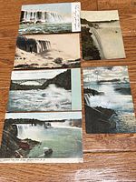 Fronts of six Niagara Falls postcards displayed on wood surface