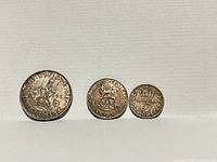 Front view of three British silver coins—1945 shilling, 1919 sixpence, 1917 threepence—standing edge-on against white background