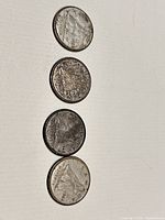 Four Canadian dimes laid vertically showing reverse side