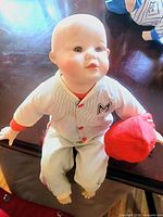 Doll in white pinstripe uniform holding red plush ball