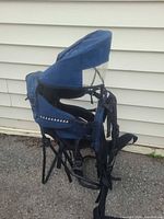 Side view showing blue framed baby carrier backpack, kickstand deployed