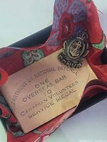 Front view of sterling RCNVR brooch with envelope in cloth-lined box