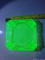 Ashtray glowing under UV light with tape showing size