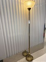 Full view of brass torchiere lamp showing base, pole, and shade