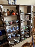 Front view showing both tall wood-grain laminate bookcases filled with assorted items