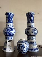 Front view of two tall segmented blue-and-white dragon vases and small jar