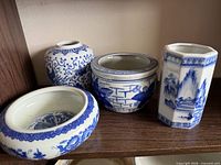 Group of four blue and white porcelain pieces on shelf
