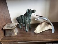 Cast iron horse, brass candle stand, and Hoselton goose sculpture grouped on shelf