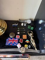 Overview of watches, cufflinks, bottle opener, lapel pins and patch