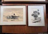 Both framed paintings side by side on table