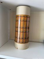Full view of thermos standing upright showing plaid design