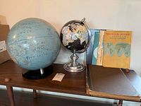 Overall shot of both globes and three atlas items on table