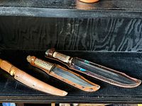 All three knives in sheaths on shelf