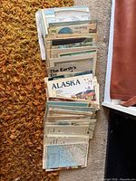 Stack of numerous National Geographic folded maps and booklets on floor