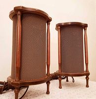 Pair of cylindrical wooden speakers showing design, wires, and mounting hooks