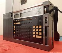 Left front view of Sony ICF-2010 showing speaker, keypad, display, and new antenna