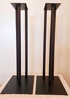 Front view of both tall black metal speaker stands