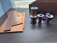 Five copper wire spools and copper plates on tabletop