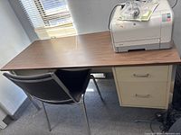 Desk top surface with printer, showing laminate and portion of chair